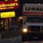 U-Haul truck driving through Toledo during police chase near McDonald’s sign at dusk.