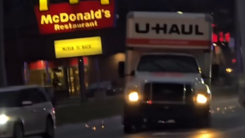 U-Haul truck driving through Toledo during police chase near McDonald’s sign at dusk.